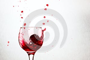 Lot of bright drops of red wine flying out of a glass