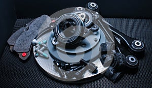 Lot of car parts running gear: brake disc, pads and hub bearing with fasteners, isolated on a black background