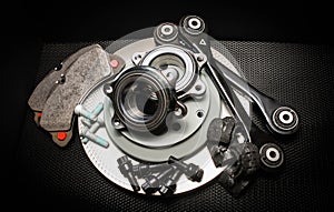 Lot of car parts running gear: brake disc, pads and hub bearing with fasteners, isolated on a black background