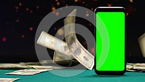 Lot of cash lying near smartphone with green screen, online winnings, casino app