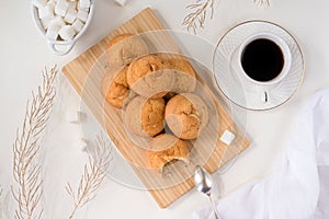 a lot of cheese biscuit cookies on a wooden cutting board, a white cup of coffee and saucers, refined sugar, dry twigs