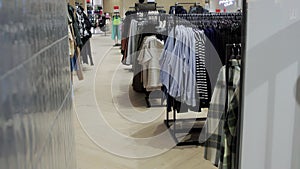 A lot of clothes, T-shirts and shirts hanging on hangers are sold in a modern clothing store, stylish interior. Slow