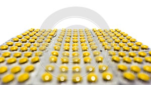 A lot of color yellow round tablets in a packs in a row. Pharmaceuticals and pills on a white background