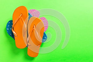 A lot of colored flip flops on green background. Top view with copy space