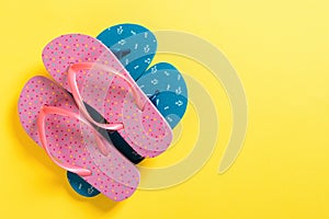 A lot of colored flip flops on yellowbackground. Top view with copy space