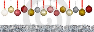 A lot of colorful Christmas baubles hanging on a ribbon over a silver tinsel, isolated on a white background with a clipping path