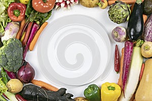 A lot of colorful fresh vegetable flat lay frame with round white plate inside. Healthy diet. Healthy cooking concept.