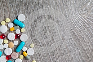 Lot of colorful medication and pills from above on grey wooden background. Copy space. Top view, frame. Painkillers, tablets, gene