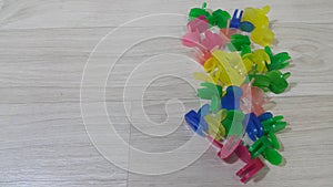 A lot of colorful small holding clips placed on a wooden floor