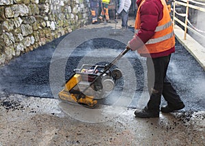 Lot of construction workers working and making a mini-roller asphalt road