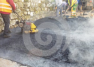 Lot of construction workers working and making a mini-roller asphalt road