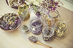 Lot of different dry herbal remedy plants in glass containers.