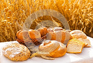 Lot of different flavored bread, wheat, rye, on the table in the field outside