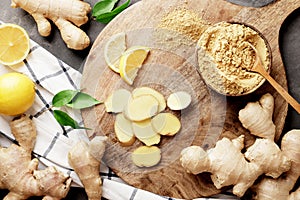 A lot of different ginger on a wooden kitchen board with lemons. Ginger dry and fresh, slides of ginger and lemons. A bowl full of