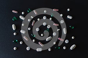 A lot of different pink, green and white coloured pills making mosaic on black matte background.  Healthcare and medical concept.