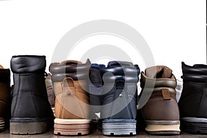 A lot of different shoes stand flush, the reverse side, in a row on a wooden board, concept, assortment of boots