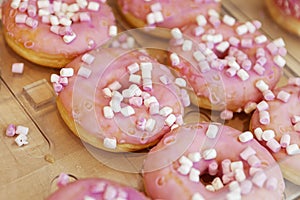 A lot of donuts with pink icing on the counter in a store. Traditional mouth-watering sweets. Close-up