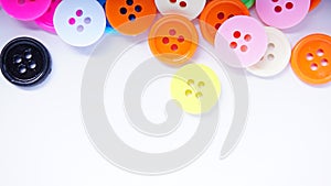 A lot of full spectrum multi colored vintage clothing plastic buttons randomly scattered on the white background - top view