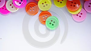 A lot of full spectrum multi colored vintage clothing plastic buttons randomly scattered on the white background - top view