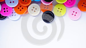 A lot of full spectrum multi colored vintage clothing plastic buttons randomly scattered on the white background - top view