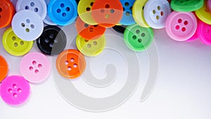 A lot of full spectrum multi colored vintage clothing plastic buttons randomly scattered on the white background - top view