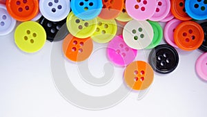 A lot of full spectrum multi colored vintage clothing plastic buttons randomly scattered on the white background - top view