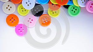 A lot of full spectrum multi colored vintage clothing plastic buttons randomly scattered on the white background - top view