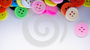 A lot of full spectrum multi colored vintage clothing plastic buttons randomly scattered on the white background - top view