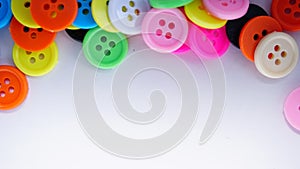 A lot of full spectrum multi colored vintage clothing plastic buttons randomly scattered on the white background - top view