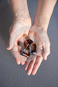 A lot of glass bottles of essential oils in the hands of a woman