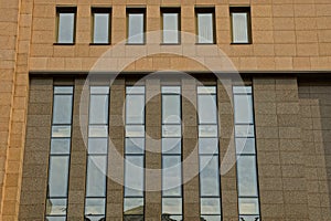 A lot of glass windows on the facade of a brown high-rise building