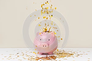 A lot of gold coins falling into a piggy bank