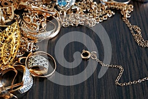 a lot of gold jewelry chains, rings, earrings, bracelets, lie on a dark wooden table, pawnshop concept, copy space