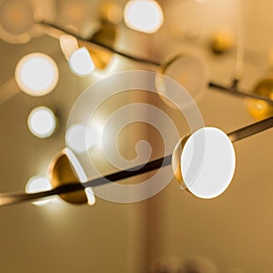 A lot of golden small spot luminaires turned on with white light on a metal rod in the interior photo