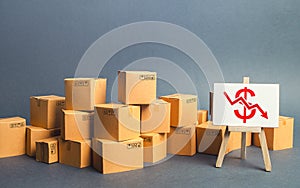 Lot of goods cardboard boxes and easel with a red dollar down arrow. Decline trade production rates, decreased sales. Low export. photo