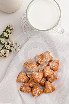 a lot of heart-shaped shortbread cookies, decorated with sesame seeds on a white table