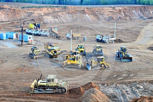 A lot of heavy construction equipment in the mining quarry. Parking with bulldozers, tractors, front loaders, excavators and dump