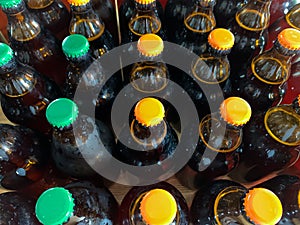 A lot of home brewery self made beer. Many brown glass craft beer bottles with green and orange corks, close up top view on a