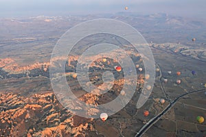 A lot of hot air balloons are flying over the valley with road in Cappadocia. Aerial photography