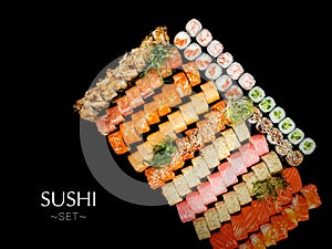 A lot of Japanese sushi roll pieces isolated on black background. Large set with salmon, tuna, shrimp, avocado, cucumber with