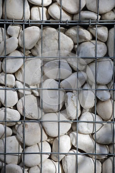 A lot of large white polished pebbles behind a metal grid