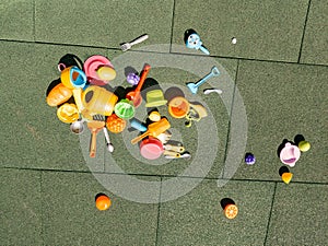 A lot of multi-colored children`s toys on the playground with a rubber coating in the courtyard. Forks, spoons, rakes, scoops,