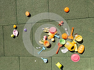 A lot of multi-colored children`s toys on the playground with a rubber coating in the courtyard. Forks, spoons, rakes, scoops,