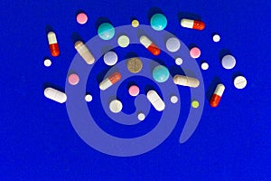 A lot of multi-colored pills on blue background, as a concept of medical treatment with a prescription.