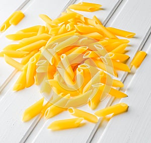 A lot of pasta is scattered on a white wooden table. The concept of eating