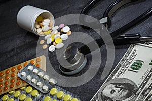 A lot of pills, a stethoscope and money on a dark table