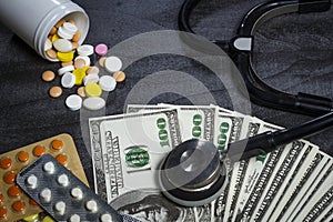 A lot of pills, a stethoscope and money on a dark table
