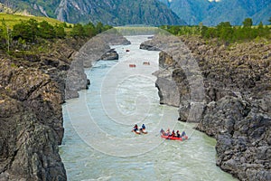 A lot of rafts and kayaks floating down a mountain river Katun. Mountain landscape.