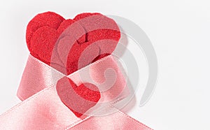 A lot of red felt hearts with a pink ribbon bow isolated on a white background on the left