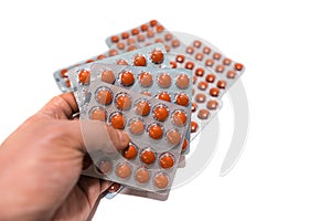 A lot of round tablets in a packs in man`s hand. Pharmaceuticals and pills on a white background